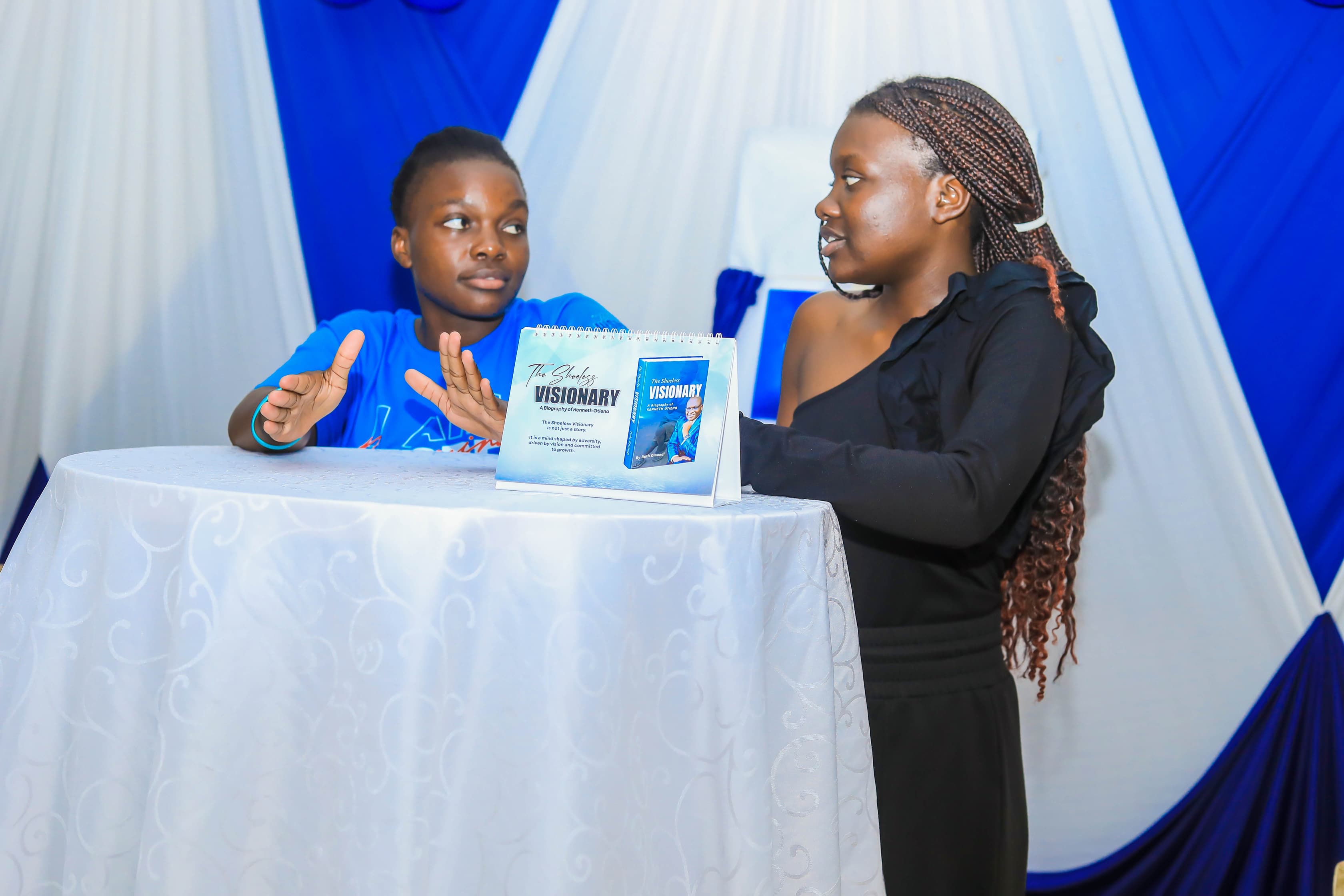 Kenneth's daughters, Kateleen and Joy, have a conversation during the official book launch event held in Kisumu City venue