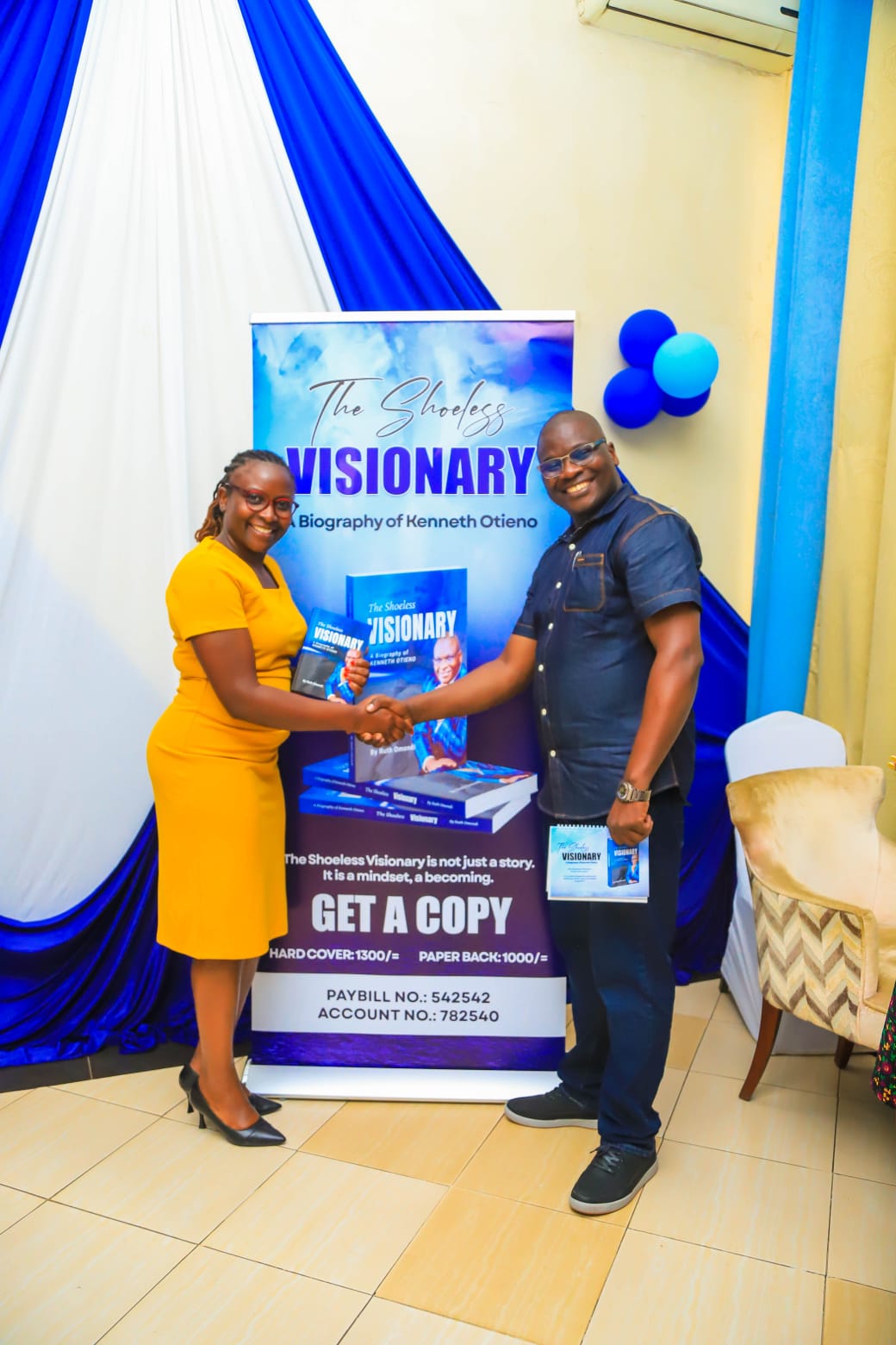 Pamela Bateta receives her copy of the book from Kenneth during the official launch event held in Kisumu City venue